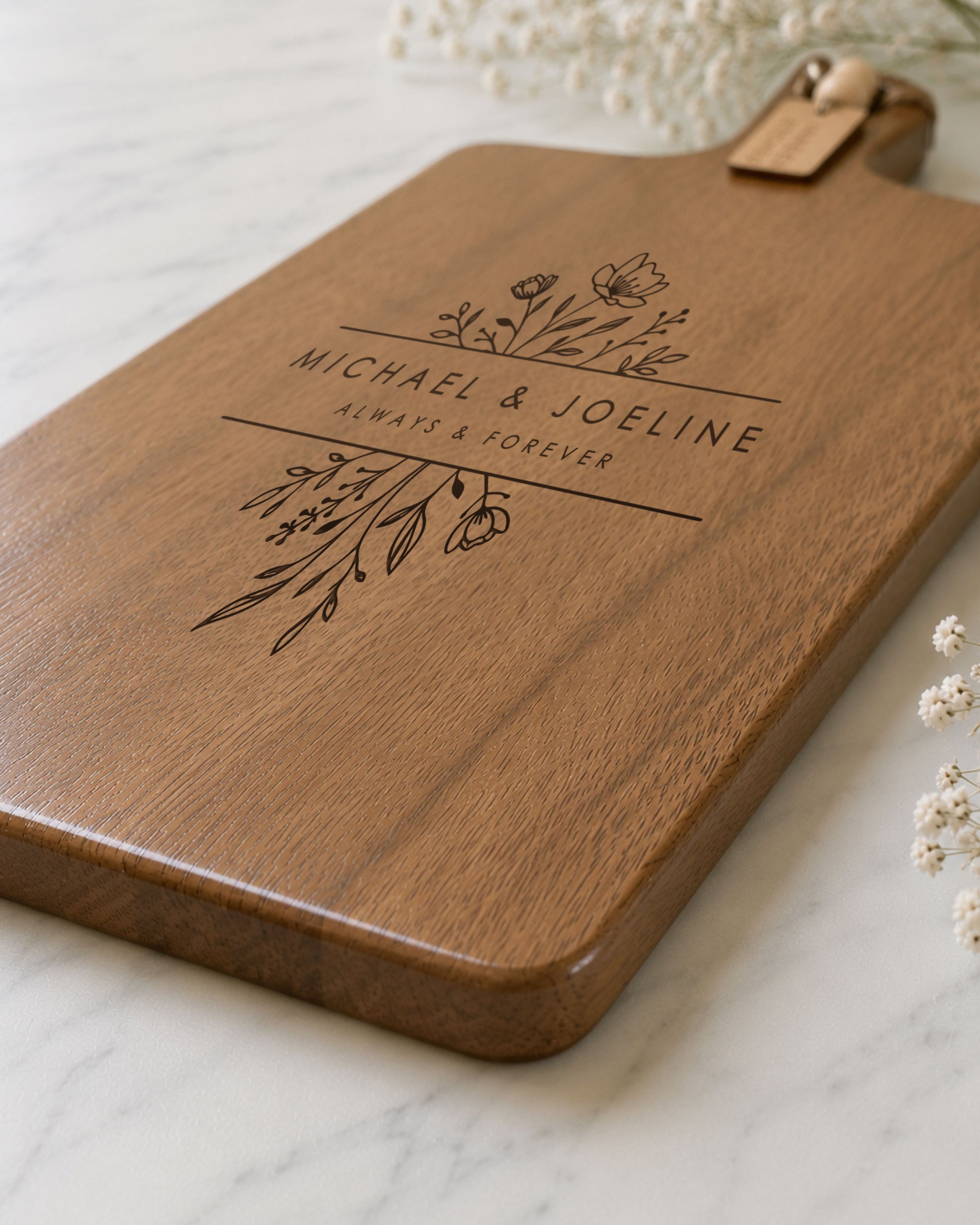Close-up of a custom charcuterie board featuring detailed floral laser engraving and personalised names on premium acacia timber.