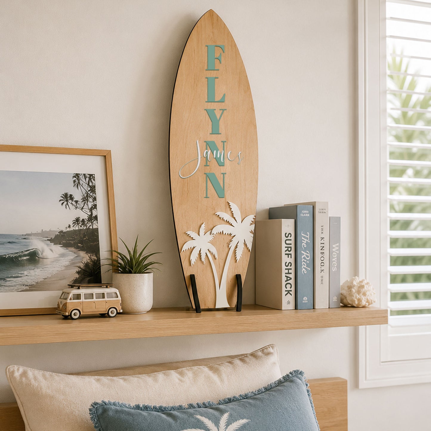Personalised wooden surfboard displayed on a shelf in a coastal beach theme bedroom with palm tree decoration and custom name.