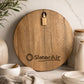 Branded round acacia serving board engraved with the SlaterAir company logo displayed in a modern kitchen.
