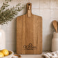 Premium acacia branded serving board with custom business logo styled against tiled kitchen splashback.