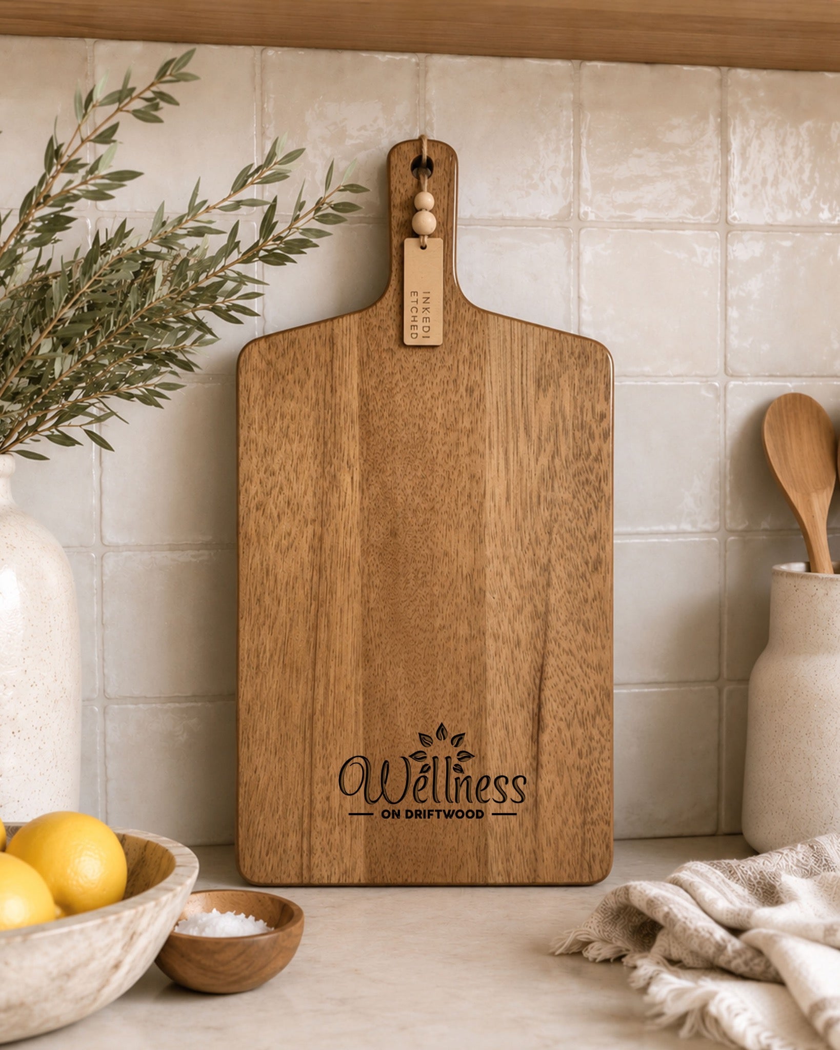 Premium acacia branded serving board with custom business logo styled against tiled kitchen splashback.