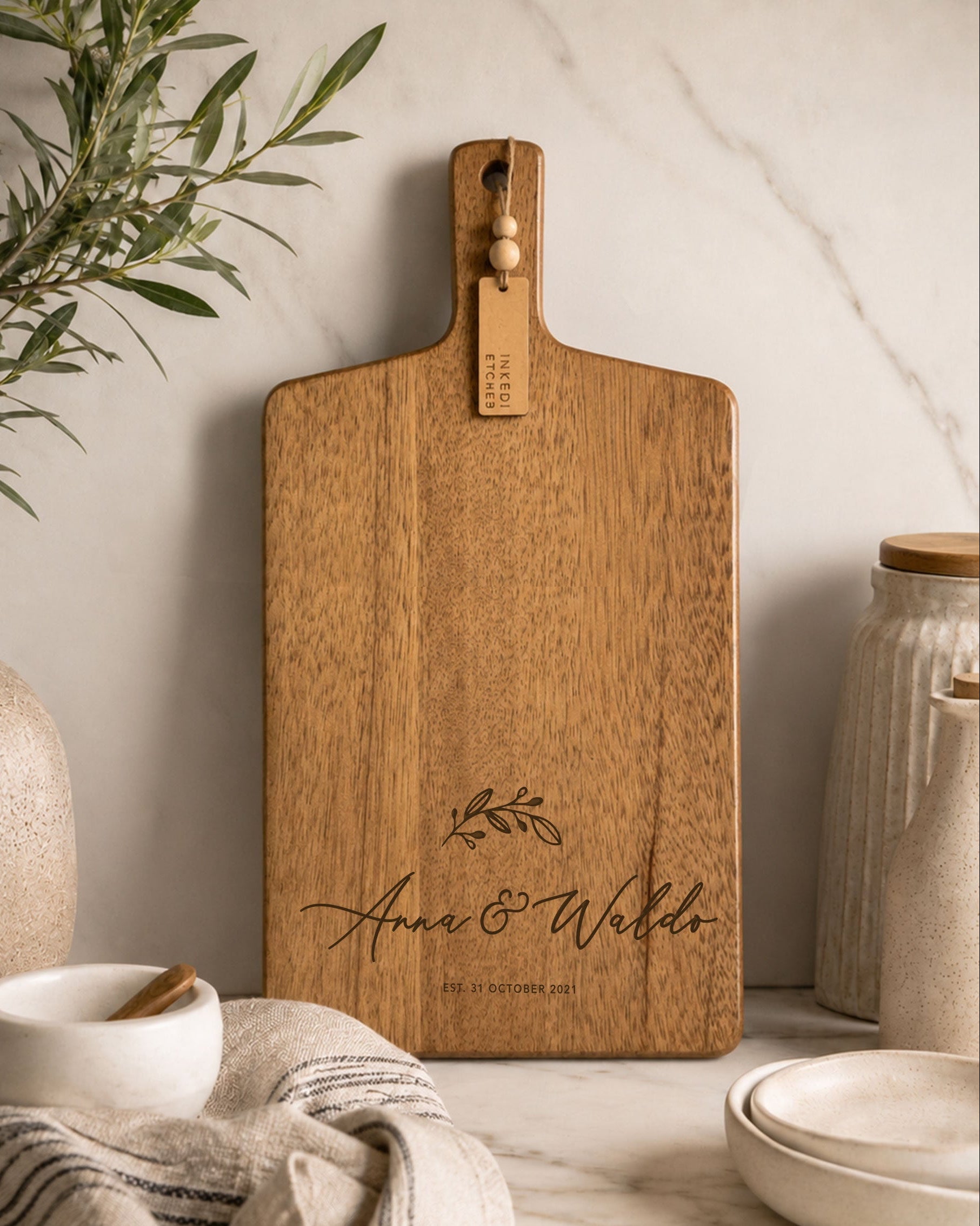 Custom engraved acacia cheese board personalised with names, styled on a marble benchtop as a wedding, anniversary or housewarming gift.
