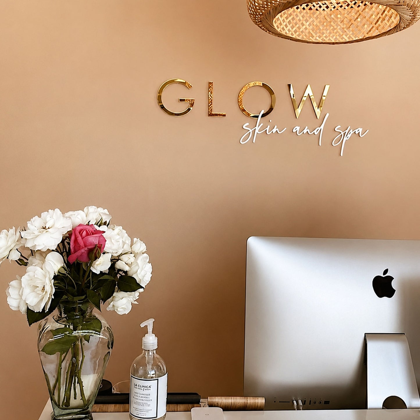 Gold mirror acrylic business logo sign installed behind a skin clinic reception desk for luxury wall branding.
