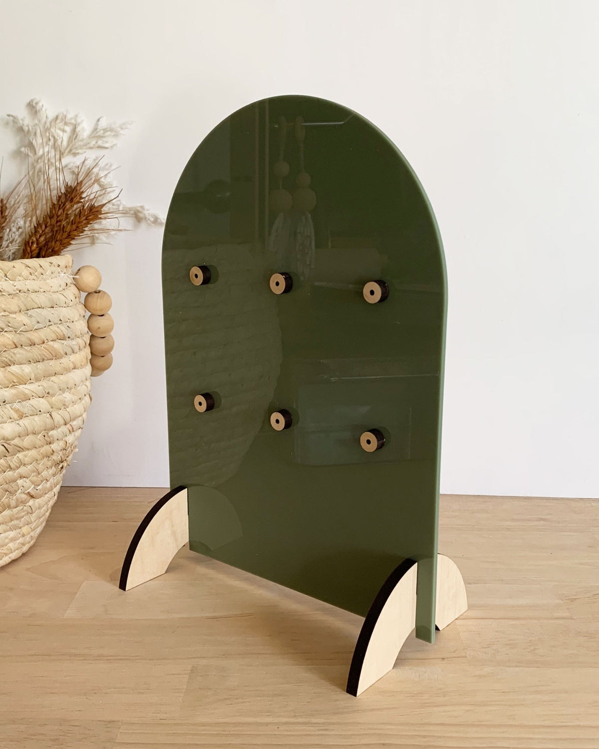 Rear view of an olive green keyring display stand with timber feet.
