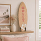 Large personalised wooden surfboard wall decor with hibiscus flower displayed on a shelf in a coastal style children's bedroom.