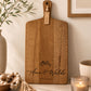 Personalised acacia serving board engraved with names and wedding date displayed in a modern neutral kitchen with candle and timber décor.