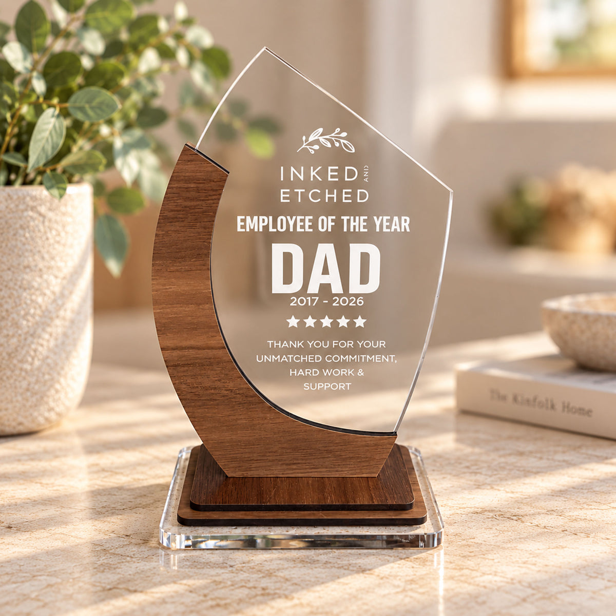 Timber and clear acrylic employee award personalised for Dad, displayed on a stone tabletop beside greenery in warm natural light.