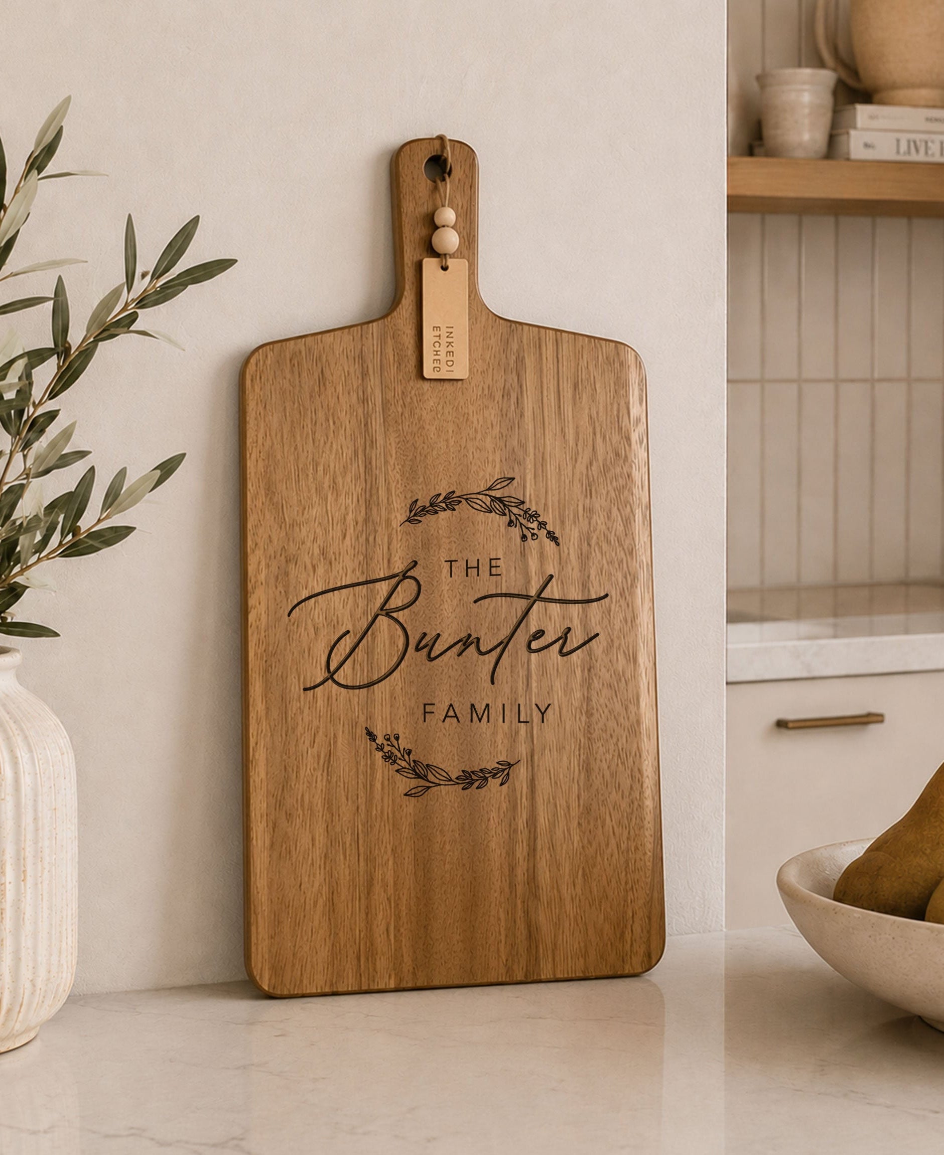 Personalised engraved acacia serving board displayed in a modern kitchen with custom family name engraving.