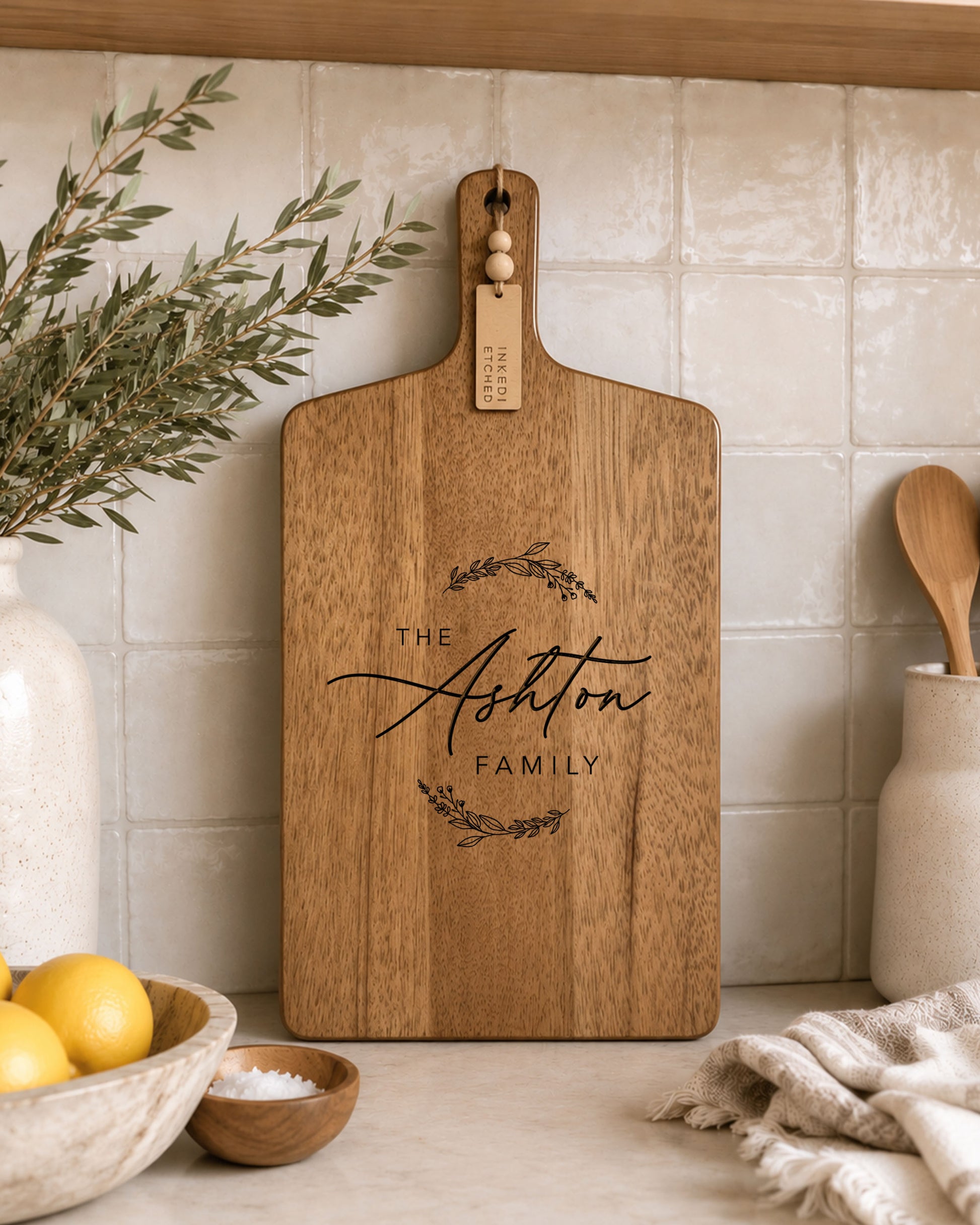 Personalised engraved acacia serving board displayed in a modern kitchen with custom family name engraving.