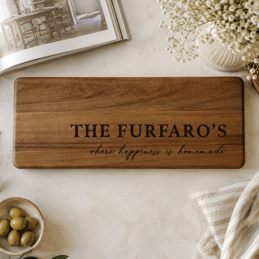 Personalised acacia serving platter engraved with a family name and custom message displayed on a modern kitchen countertop.