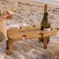 Personalised foldable wooden wine picnic table on the beach with a wine bottle, wine glass and picnic blanket, perfect for outdoor wine and cheese picnics.
