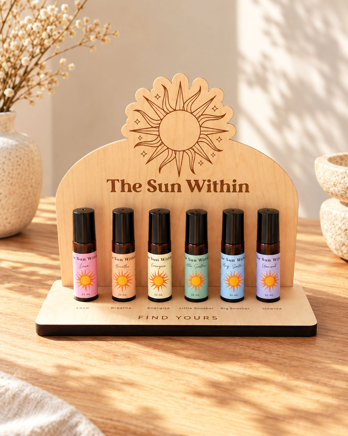 Wooden essential oil display stand holding six 10ml aromatherapy roller bottles on a wooden tabletop.